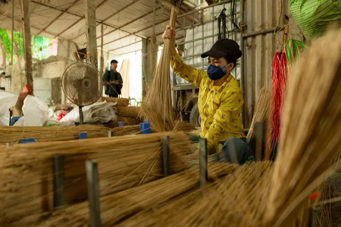 Artisan bundling dried coconut lidi for broom-making